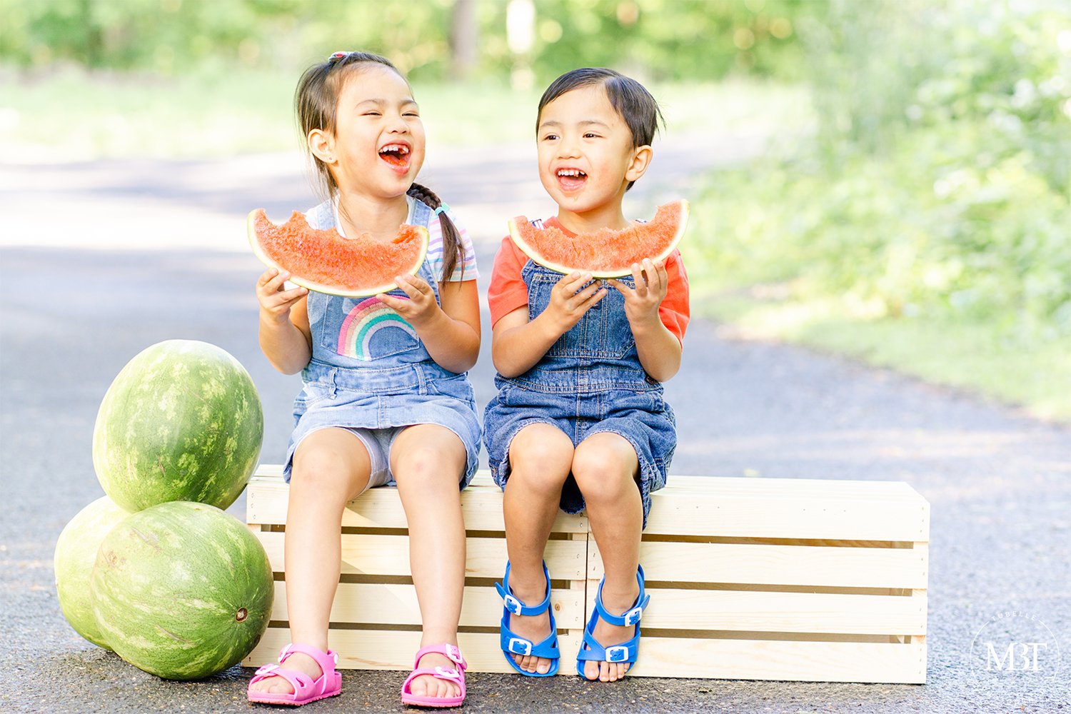 summer watermelon mini session of siblings dressed in denim overalls, eating watermelon while laughing, taken in Ellanor Lawrence Park in Chantilly, Virginia by TuBelle Photography a Northern Virginia family photographer