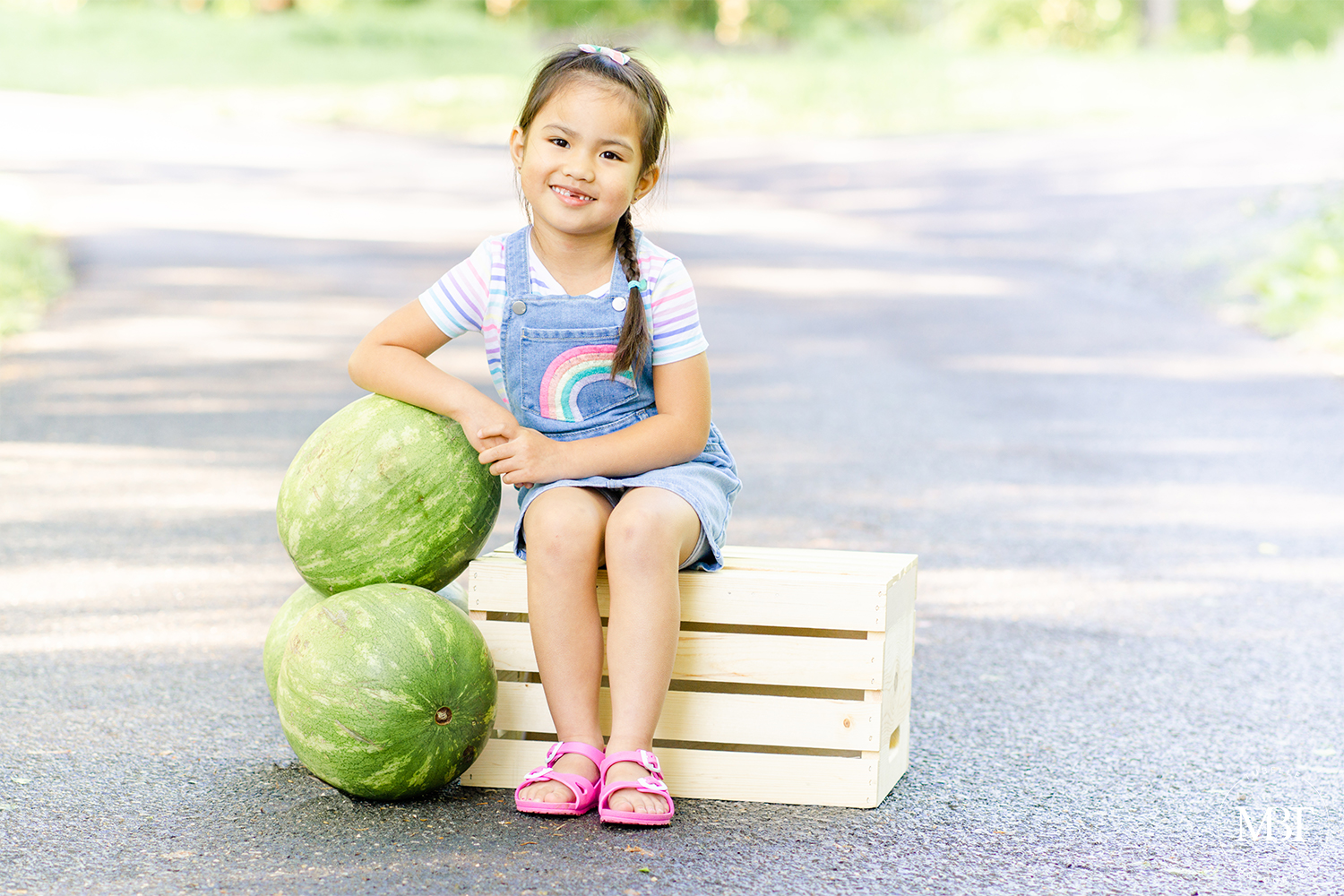 summer watermelon mini session of a girl dressed in denim overalls, smiling while resting her arm on watermelons, taken in Ellanor Lawrence Park in Chantilly, Virginia by TuBelle Photography a Fairfax-based family photographer