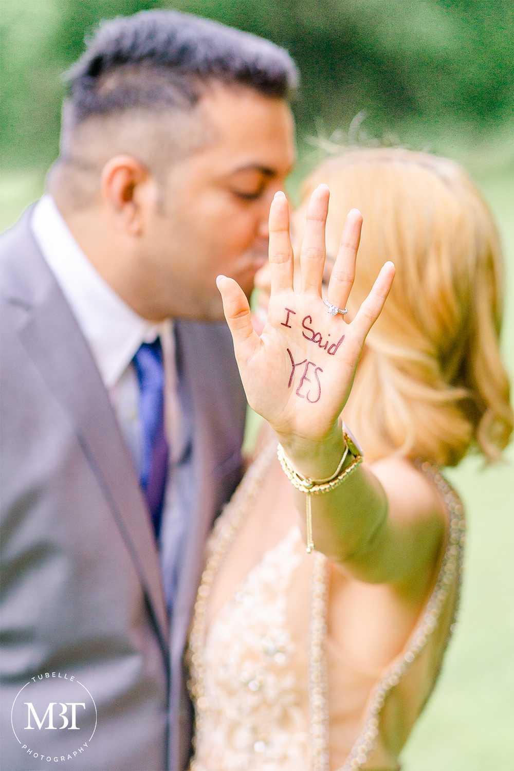 engagement session, groom to be kissing bride to be on the cheek, bride to be has her palm out written with "I Said Yes" showing off her engagement ring, taken in Centreville, Virginia by a Virginia engagement photographer