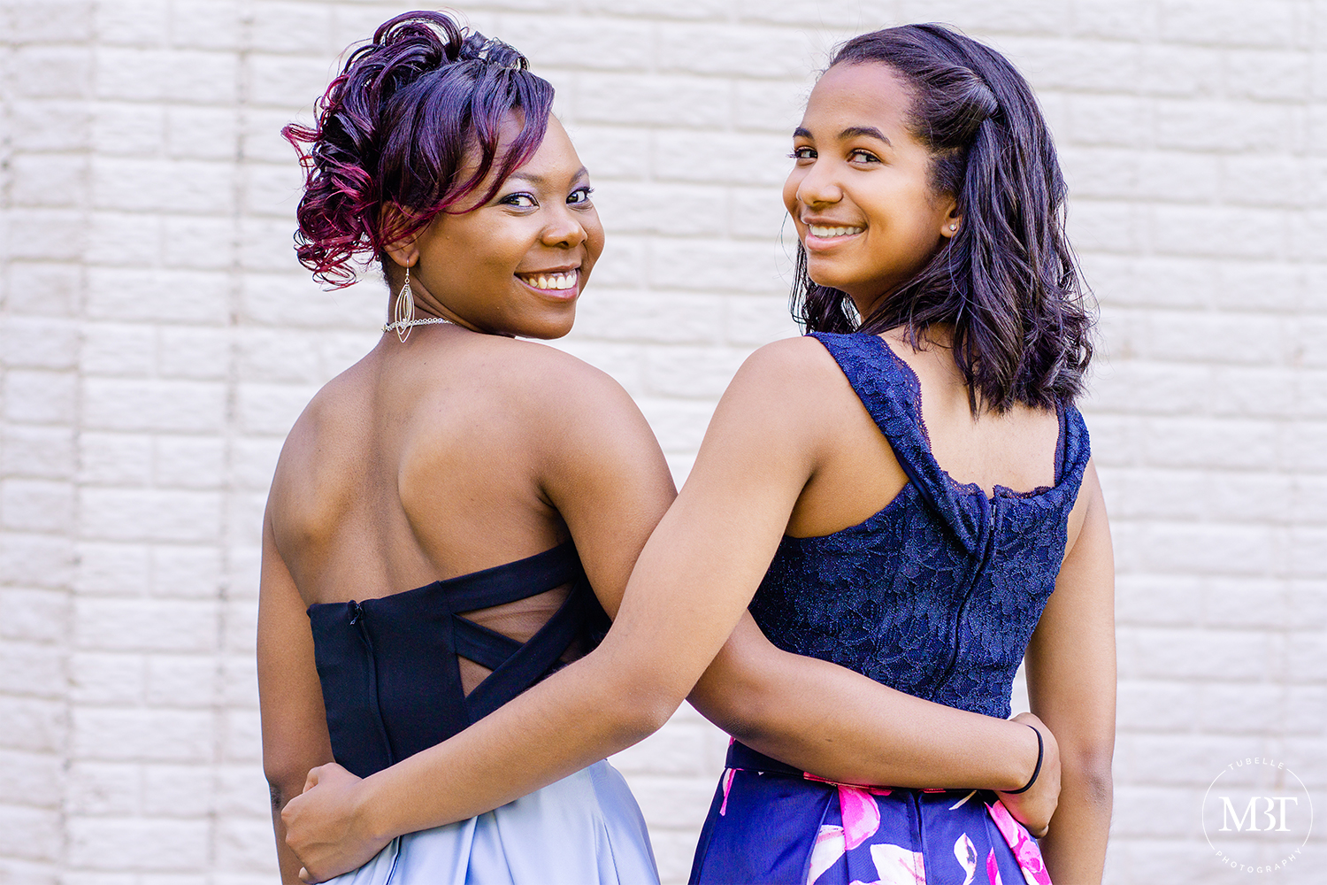 best friends looking back, smiling while they're arms at each other's waist, prom session at a backyard in Fairfax, Virginia taken by a Northern Virginia portrait photographer