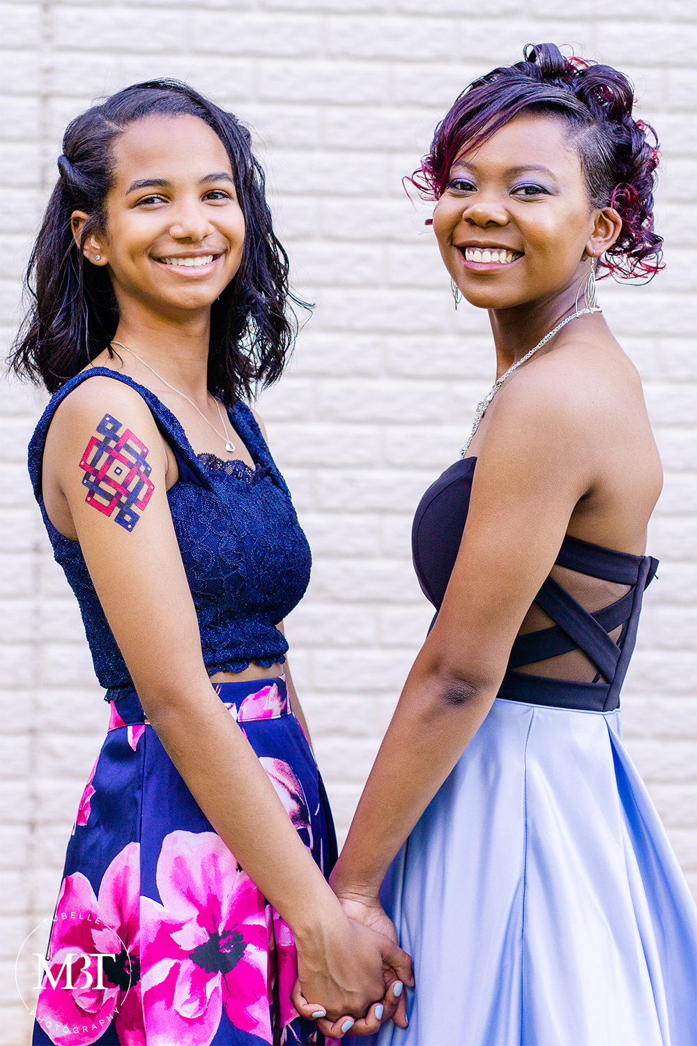 best friends prom session - they are holding each other's hands and smiling, taken at a backyard in Fairfax, Virginia taken by a Northern Virginia portrait photographer