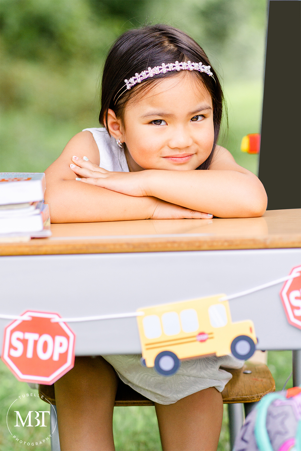 girl sitting on a school chair resting her head on her arms at a back to school mini session done in Northern Virginia by family photographer in Northern Virginia