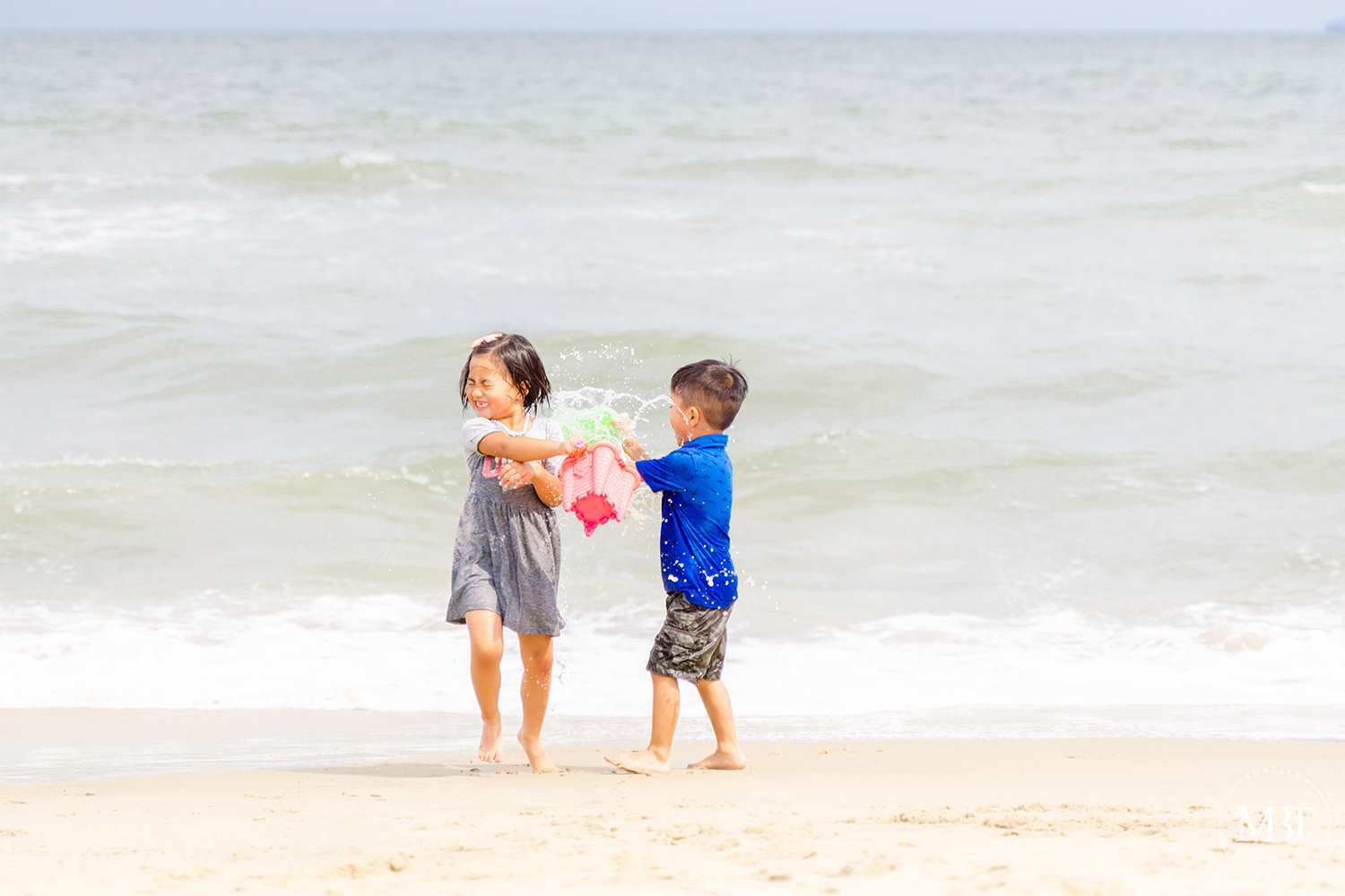 siblings playing with water at the beach, taken in Virginia Beach by a Maryland portrait photographer