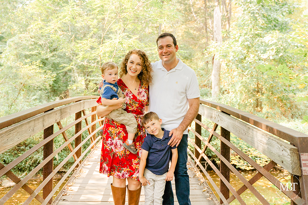 family of 4 standing by the bridge at Ellanor C. Lawrence Park in Chantilly, Virginia during their family session by a Northern Virginia family photographer