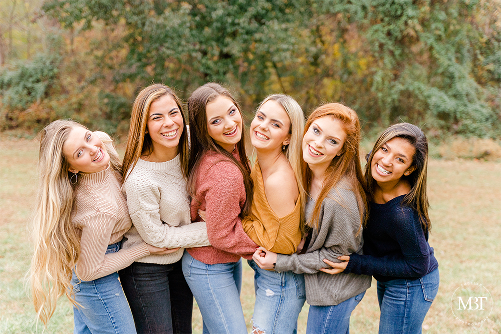 a group of teenage girls laughing while hugging each other during their senior session in Alexandria, Virginia by a Washington, DC senior photographer