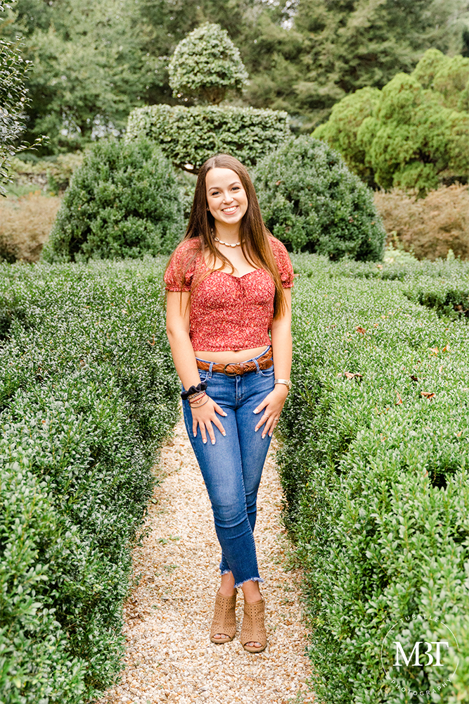 teenage girl in the middle of a garden during her senior session at Airlie in Warrenton, Virginia by a DMV senior photographer