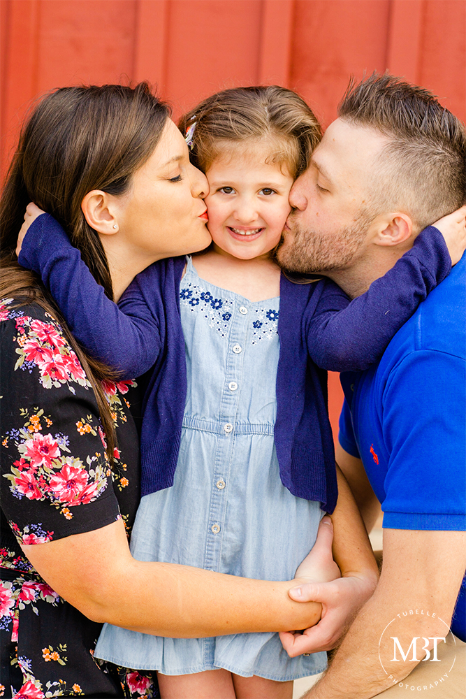 mommy & daddy kissing daughter on the cheeks during their family session in Ashburn, Virginia by a Washington, DC family photographer