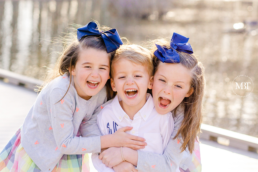siblings laughing by the bridge at Huntley Meadows Park in Alexandria, Virginia by a Northern Virginia family photographer