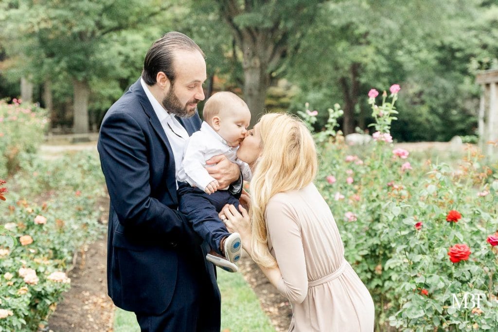 mom kissing son while held by dad during their family session in Arlington, Virginia by a NoVa family photographer