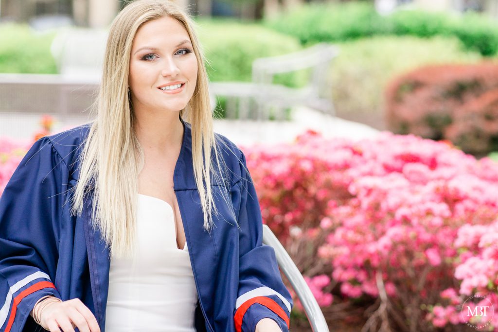 girl wearing a white dress & graduation gown during her senior session at Reston Town Center take by a Prince William County Virginia senior photographer