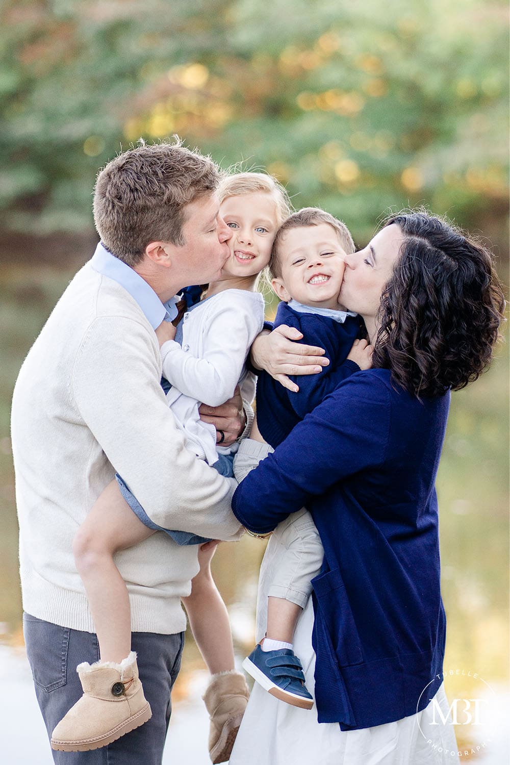mom and dad kissing kids during their family session in Sterling, Virginia, taken by TuBelle Photography, a Loudoun County family photographer