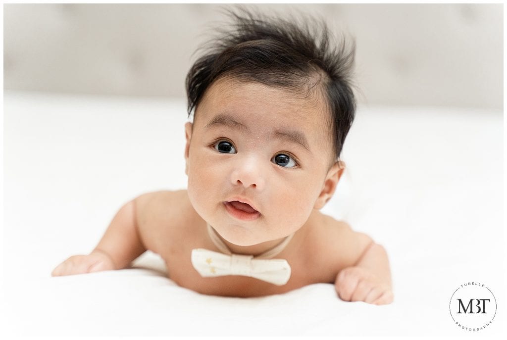 baby boy on his tummy wearing a bow tie during his milestone baby photo shoot in Mclean, Virginia by TuBelle Photography, a baby photographer in Fairfax County