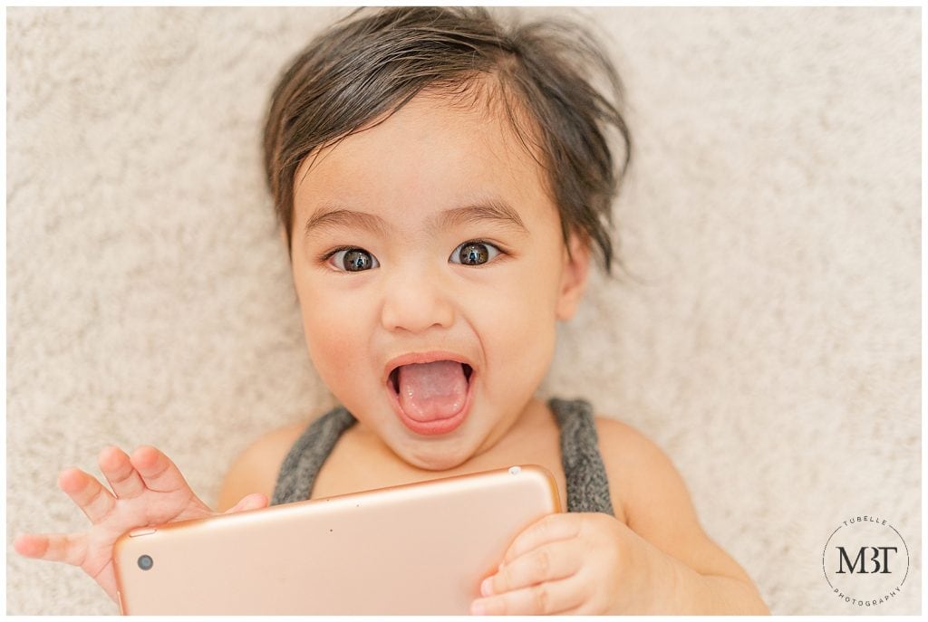 baby boy with a big smile holding an iPad during milestone pictures taken in McLean, Virginia by TuBelle Photography, a Northern Virginia milestone photographer