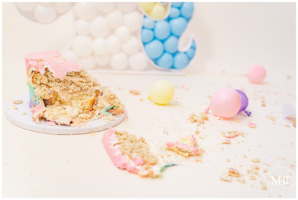 cake with crumbs on the floor during unicorn themed cake smash photos in Gainesville, Virginia taken by TuBelle Photography, a NoVa cake smash photographer