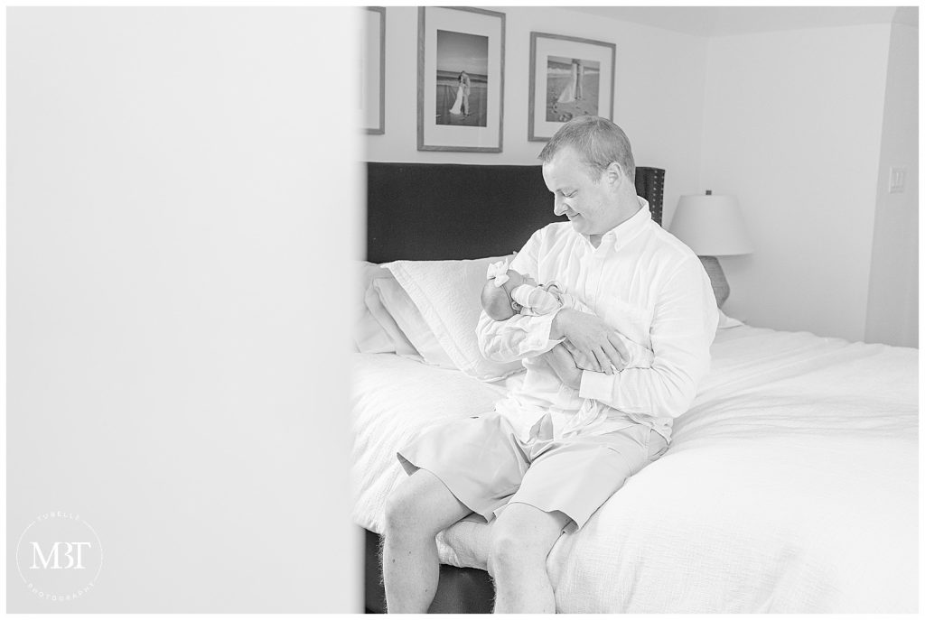 Dad smiling down at newborn baby girl during in home newborn session taken by newborn photographer TuBelle Photography in Northern Virginia