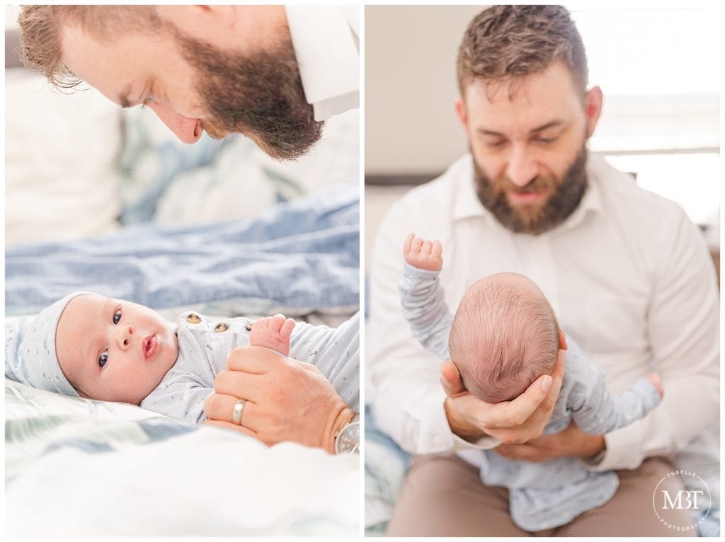 Dad looking at baby boy as he holds him in front of him and baby boy looks at camera as dad holds his hand at their Fairfax County, Virginia in home newborn pictures taken by TuBelle Photography, a DMV newborn photographer.
