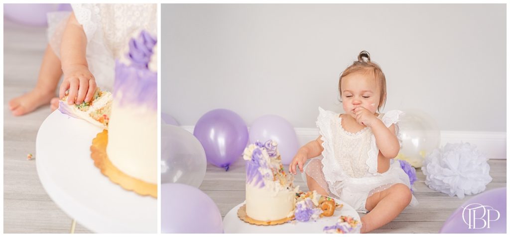 Little girl grabbing a piece of cake for cake smash pictures. Taken by TuBelle Photography, a Northern VA cake smash photographer.