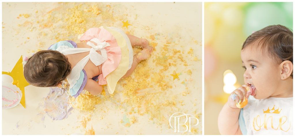 Baby girl eating cake and crawling in cake crumbs for her rainbow themed cake smash session. Taken by TuBelle Photography, a Fairfax County, Virginia cake smash photographer.