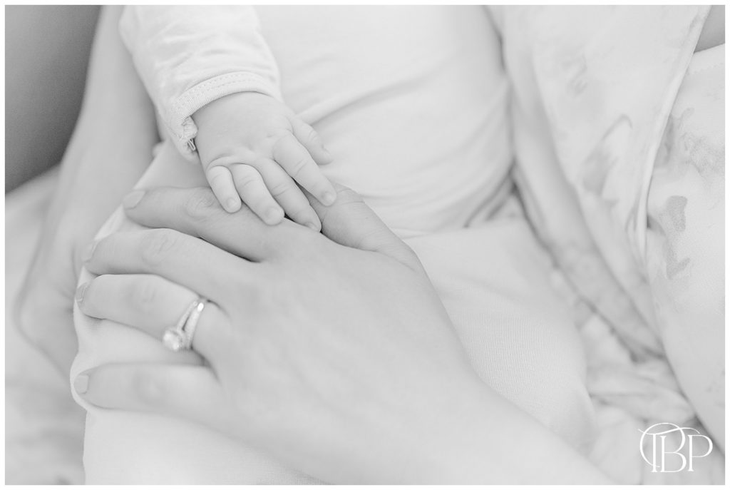 Baby girl holding her hand over mom's for her newborn session in Centerville, VA taken by TuBelle Photography.