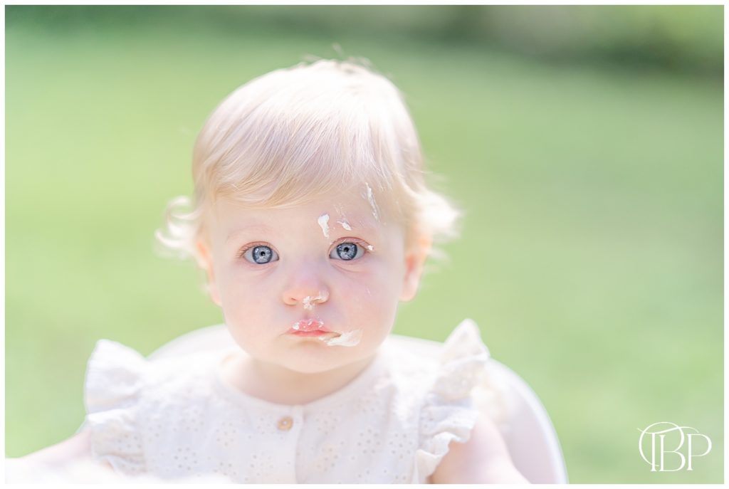 baby girl with a serious look taken at their backyard by a Warrenton, Virginia cake smash photographer