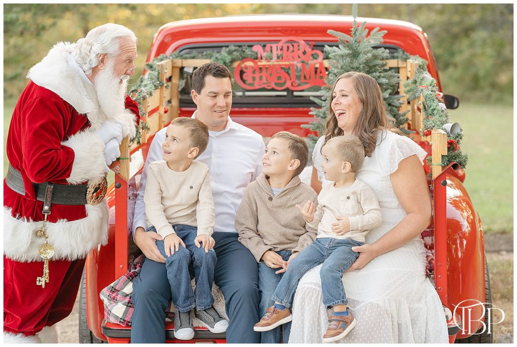 family of 5 laughing with Santa during red truck mini session taken by a NoVa photographer