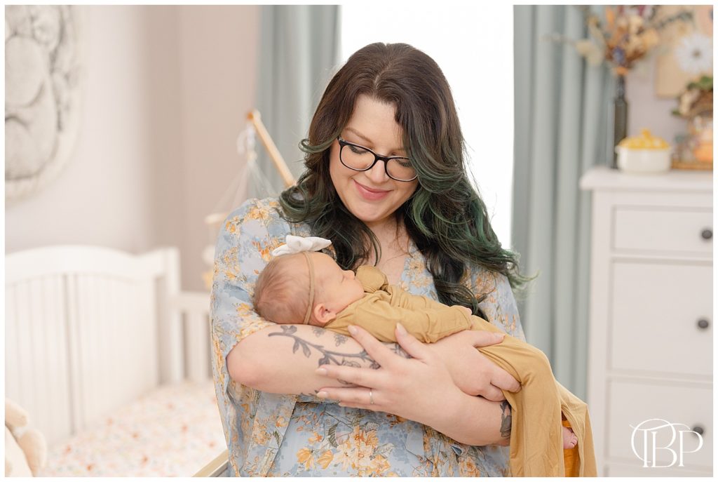 Mom holding baby in nursery during lifestyle newborn photoshoot in Haymarket, Virginia
