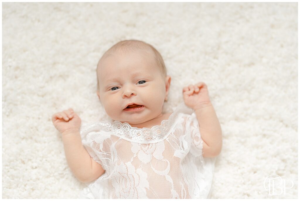 Baby girl on white carpet taken by in home newborn photographer in Chantilly, VA