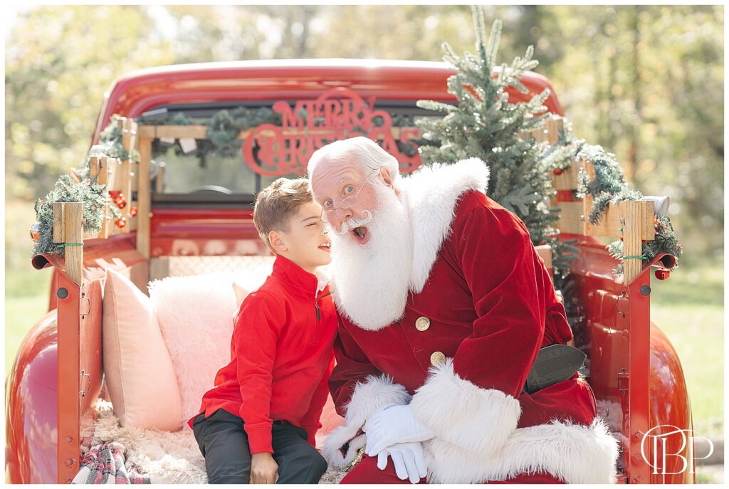 Boy whispering to Santa's ear during Fairfax County, Virginia red truck minis