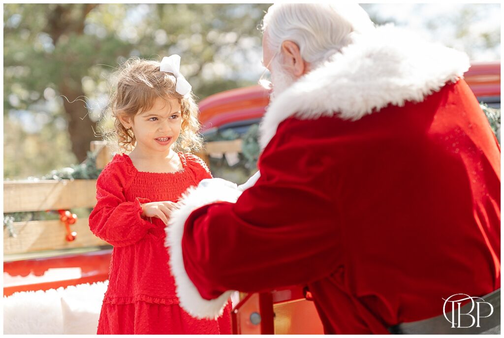 Girl playing with Santa during red truck mini session in Fairfax County, VA