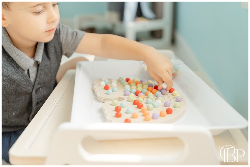 Product photo of a boy playing with rainbow activity board