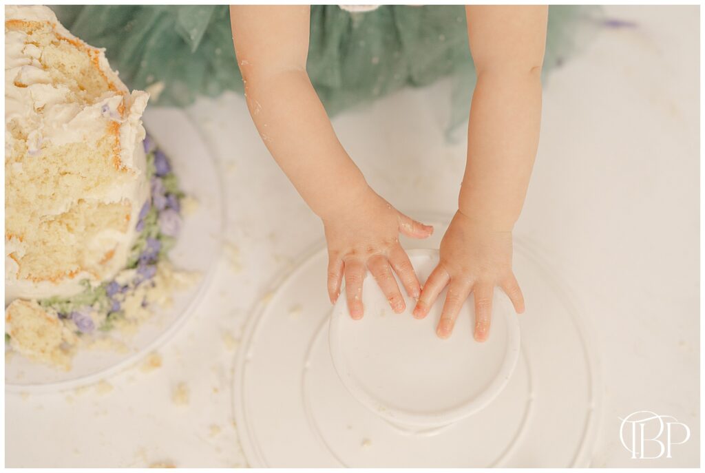Baby playing with cake stand during studio cake smash session in Bristow, VA