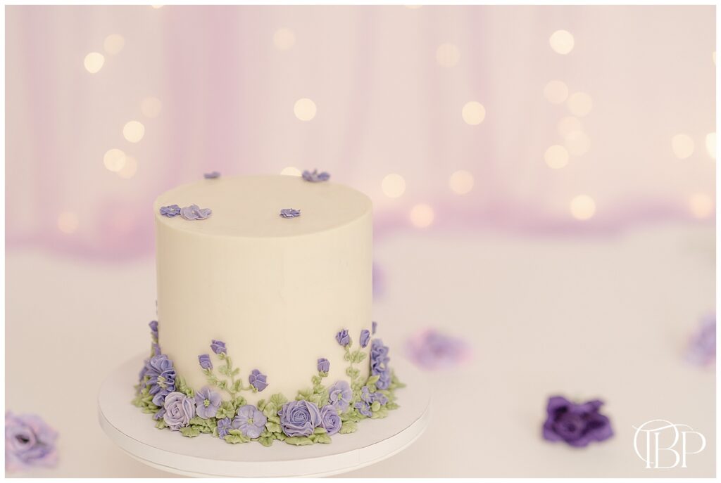 White cake with purple flower taken during studio cake smash pictures in Bristow, Virginia