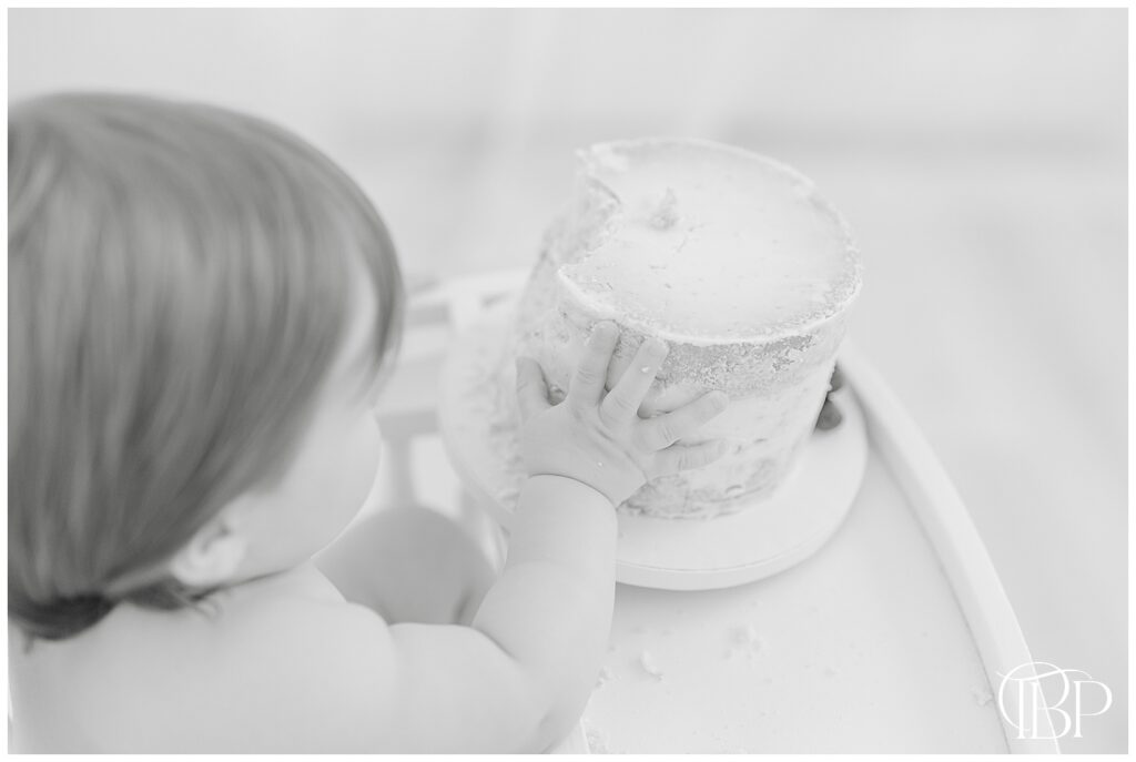 Baby touching cake during Ashburn, Virginia simple cake smash photography