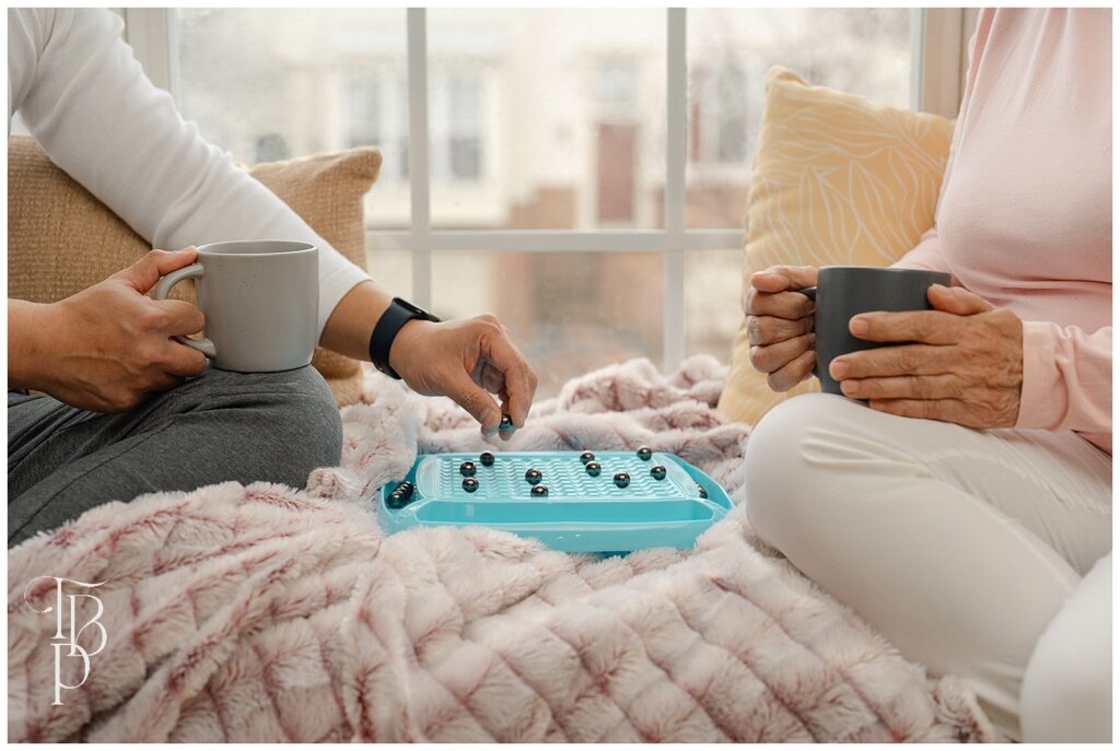 Adult and grandma playing on a rainy day while drinking coffee