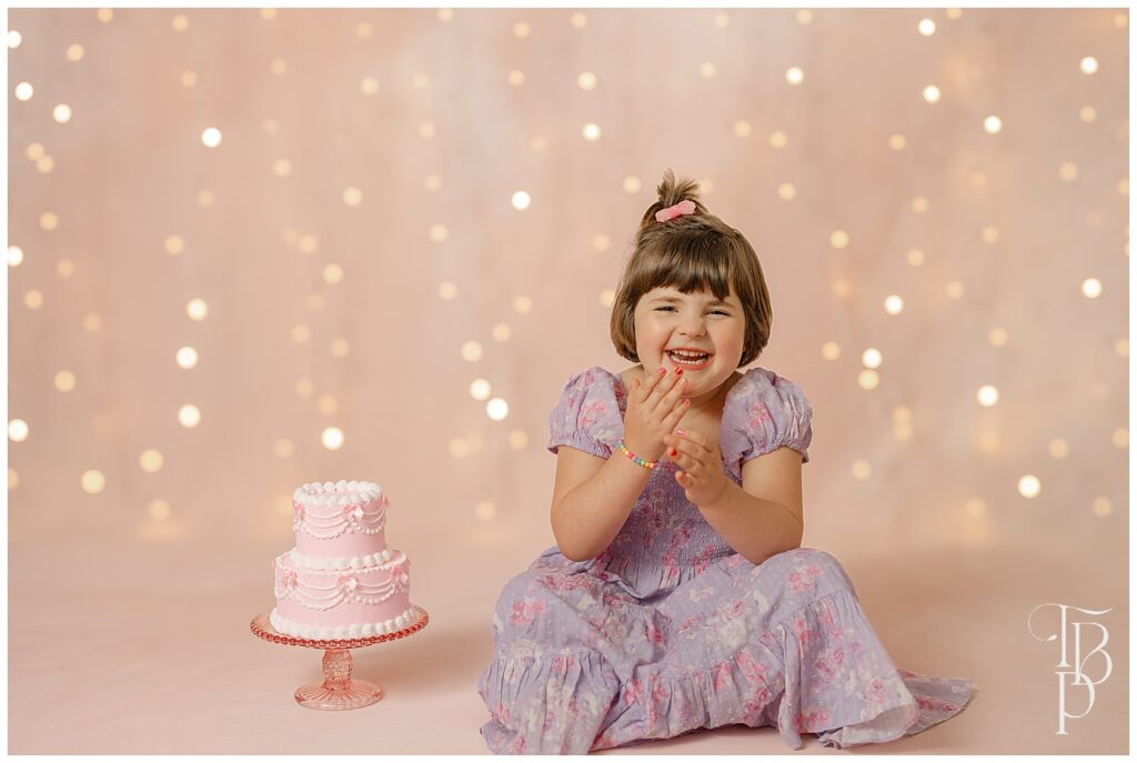 Girl laughing sitting beside a cake