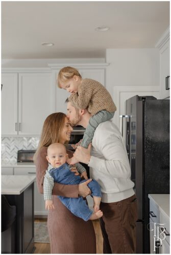 Parents holding their kids in the kitchen, during lifestyle family session