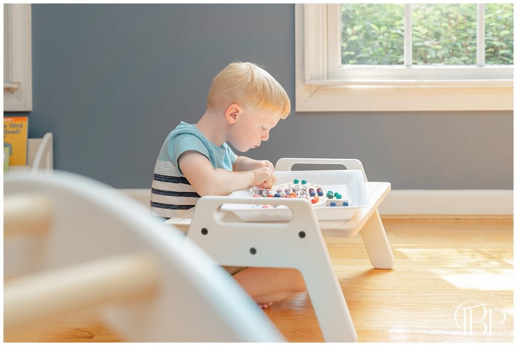 Boy playing with wooden rocketship activity board in Sterling, Virginia